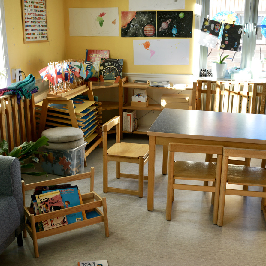 Förskolans innemiljö med bord, stolar och Montessori-material.